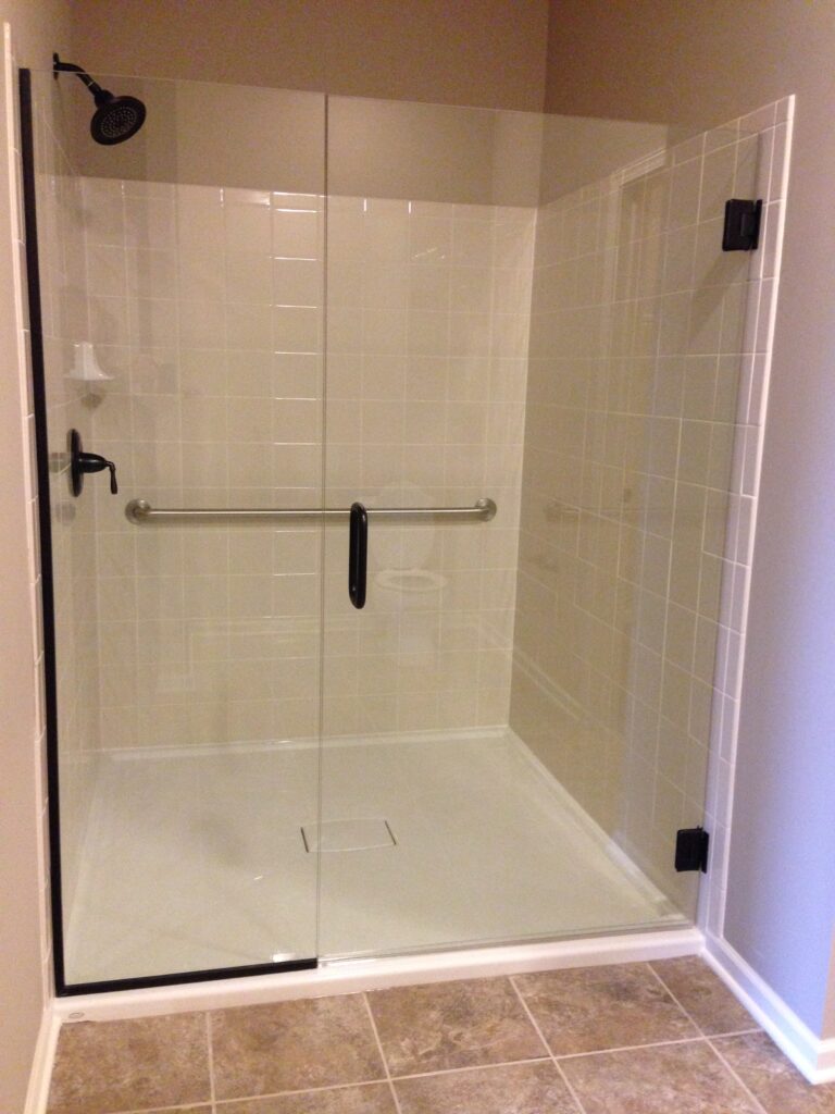 A semi-frameless sliding shower door on a new white tiled shower install.